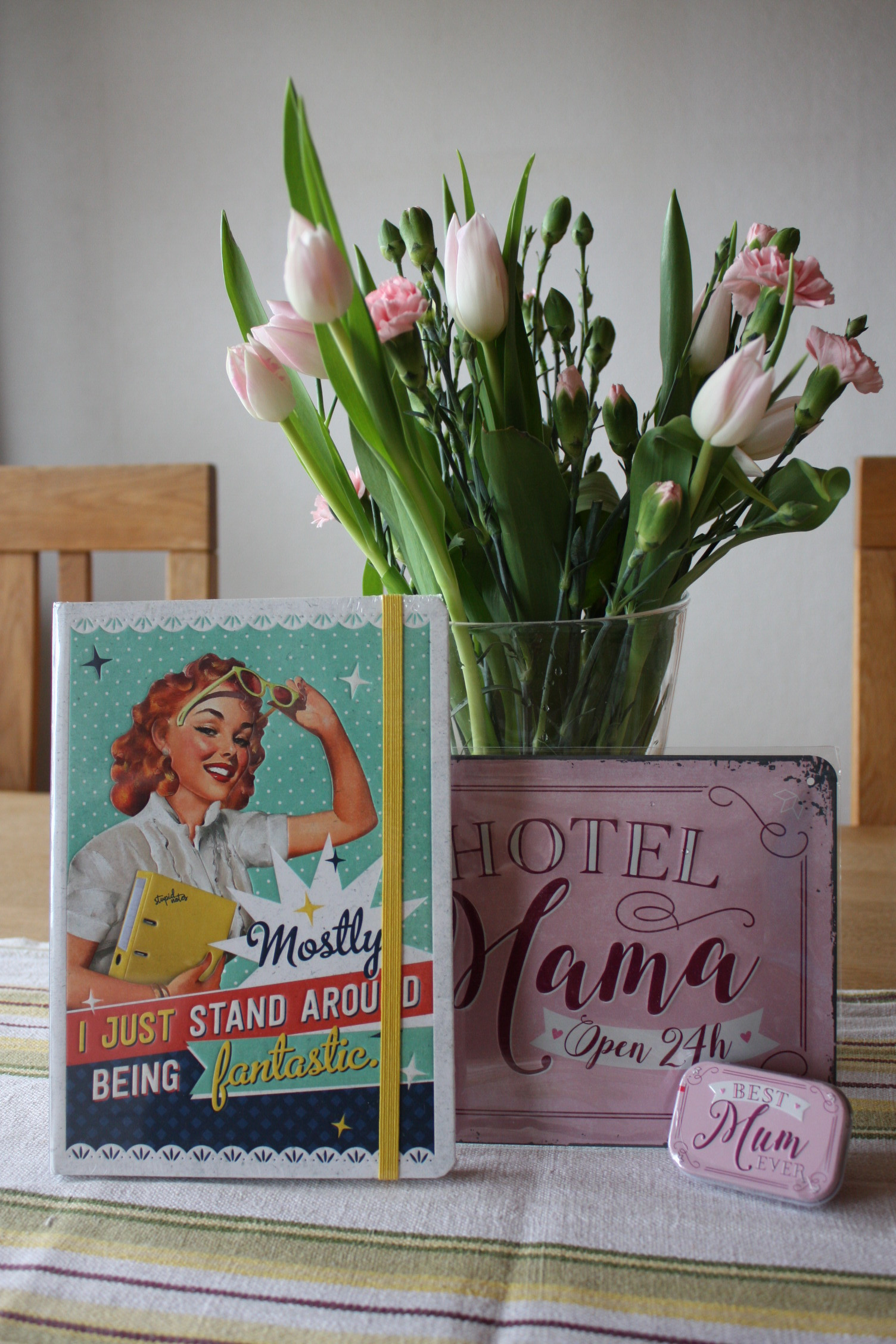 wp-image6281.png En skrivbok, en skylt och en miintask framför en bukett blommor